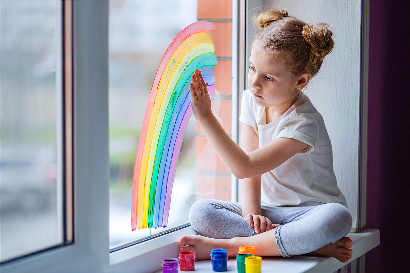 A Little Girl With Blond Hair Is Sitting In Front Of The Window The