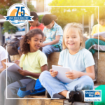 A image of a group of diverse elementary-aged students working in notebooks outside.