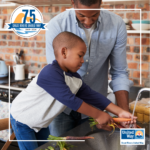 Image of an African American father and young son washing carrots in a kitchen sink.