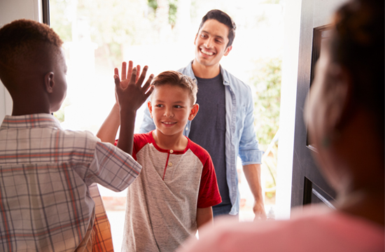 Photo of two teenage boys high-fiving with two adults in the background